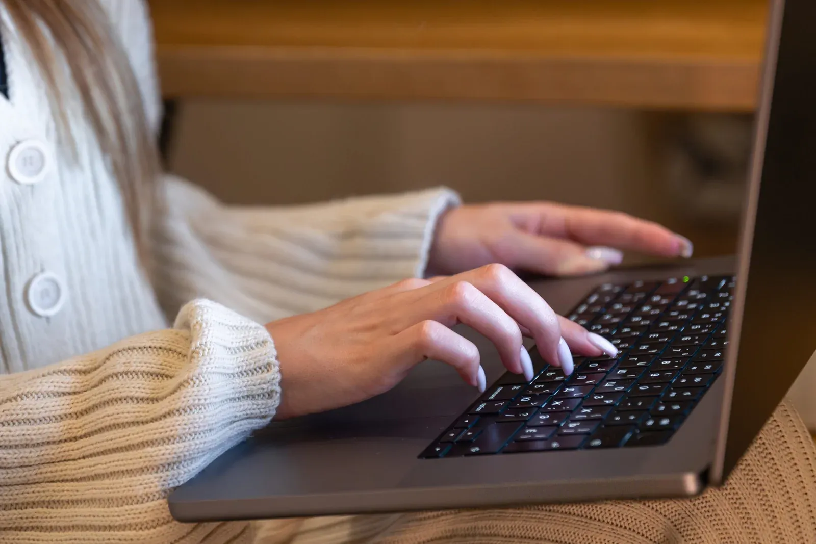 Woman typing on a laptop while sitting indoors